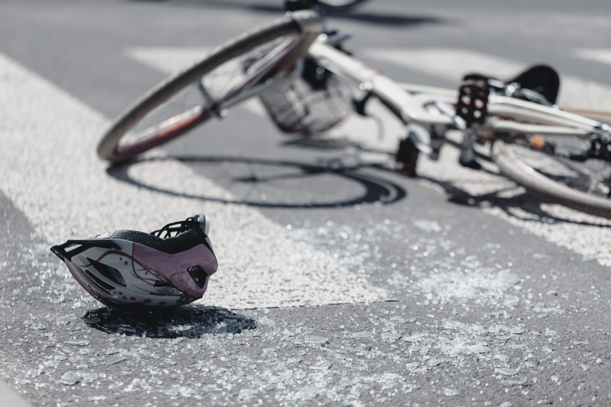 Closeup of kid's helmet and bike on a pedestrian lines after danger incident with a car